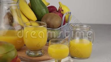 果篮和一杯果汁。新鲜芒果汁，橙汁。桌子上的水果篮。新鲜水果和果汁